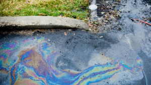 Water with oily sheen flowing along pavement